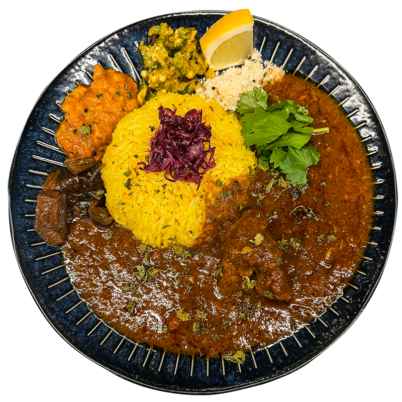 スパイスかおりのポークビンダルー。黄色いライス、副菜、パクチーを添えた一皿
